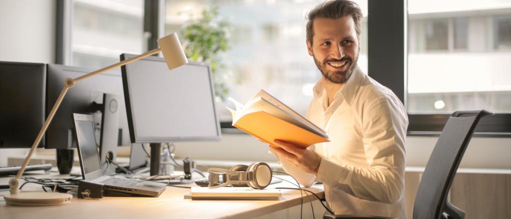 man reading book behind desk
